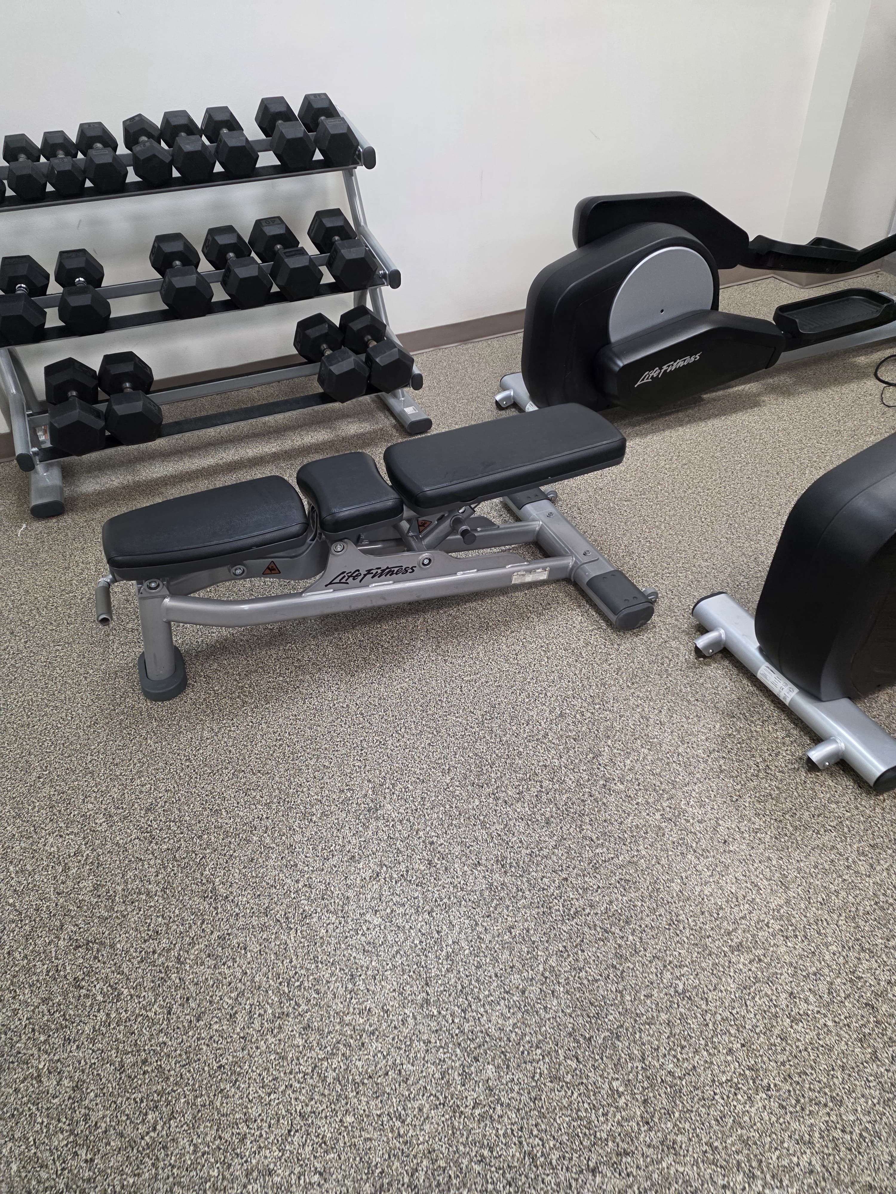 Completed client strength area with dumbbells, bench, and exercise bike