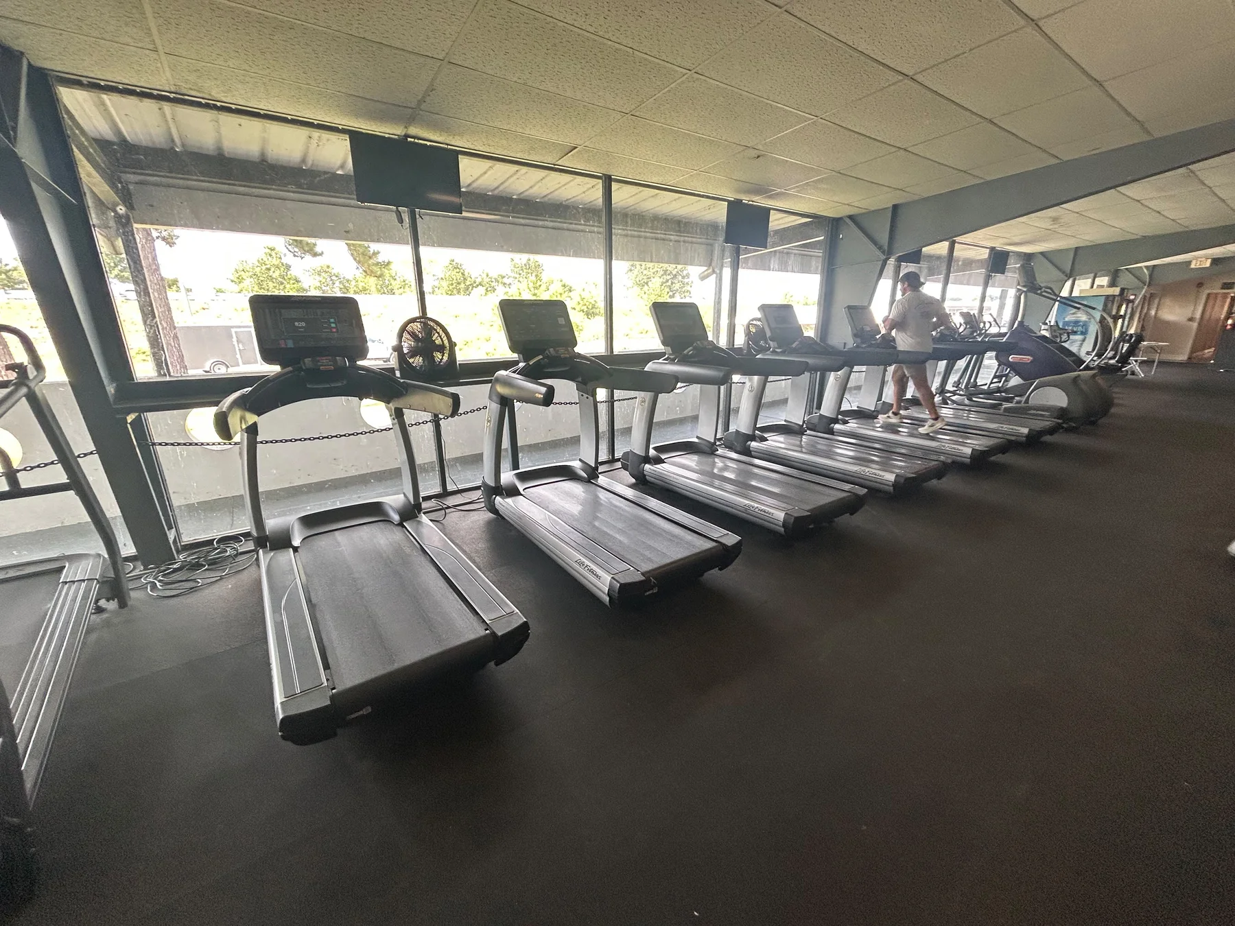 Life Fitness treadmills lined up beside the windows of a customer's gym